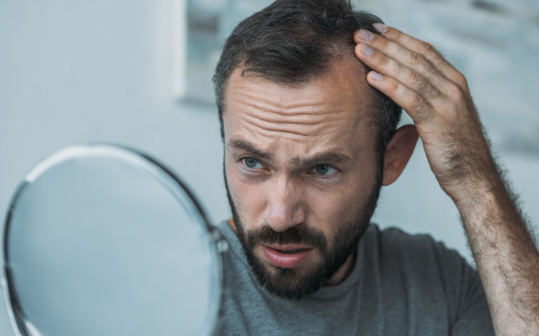 Man looking at his hairline in the mirror